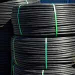 Sistema di irrigazione a goccia installato in un giardino, evidenziando piante verdi e fiori fioriti.