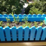 Varietà di ortaggi coltivati su un balcone, con vasi colorati e piante rigogliose.