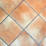 Fughe del pavimento prima e dopo il trattamento con aceto, evidenziando il bianco brillante.